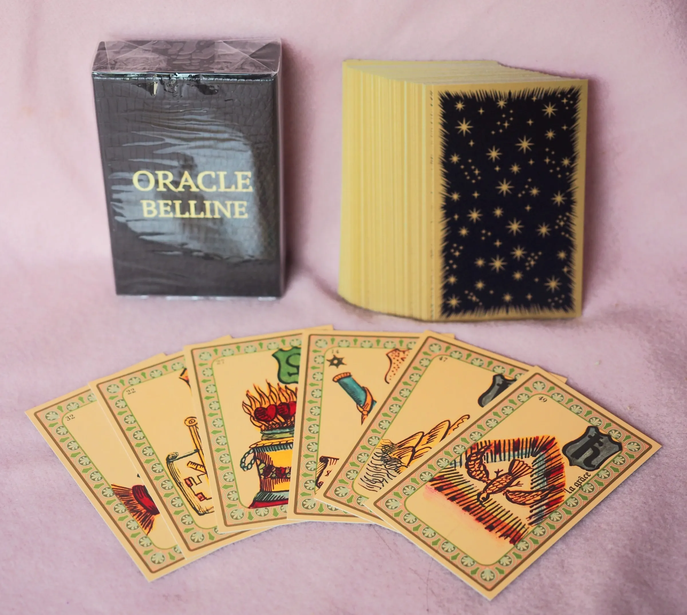 Coffret noir de l’Oracle Belline, son paquet de cartes au dos étoilé et six cartes illustrées étalées
