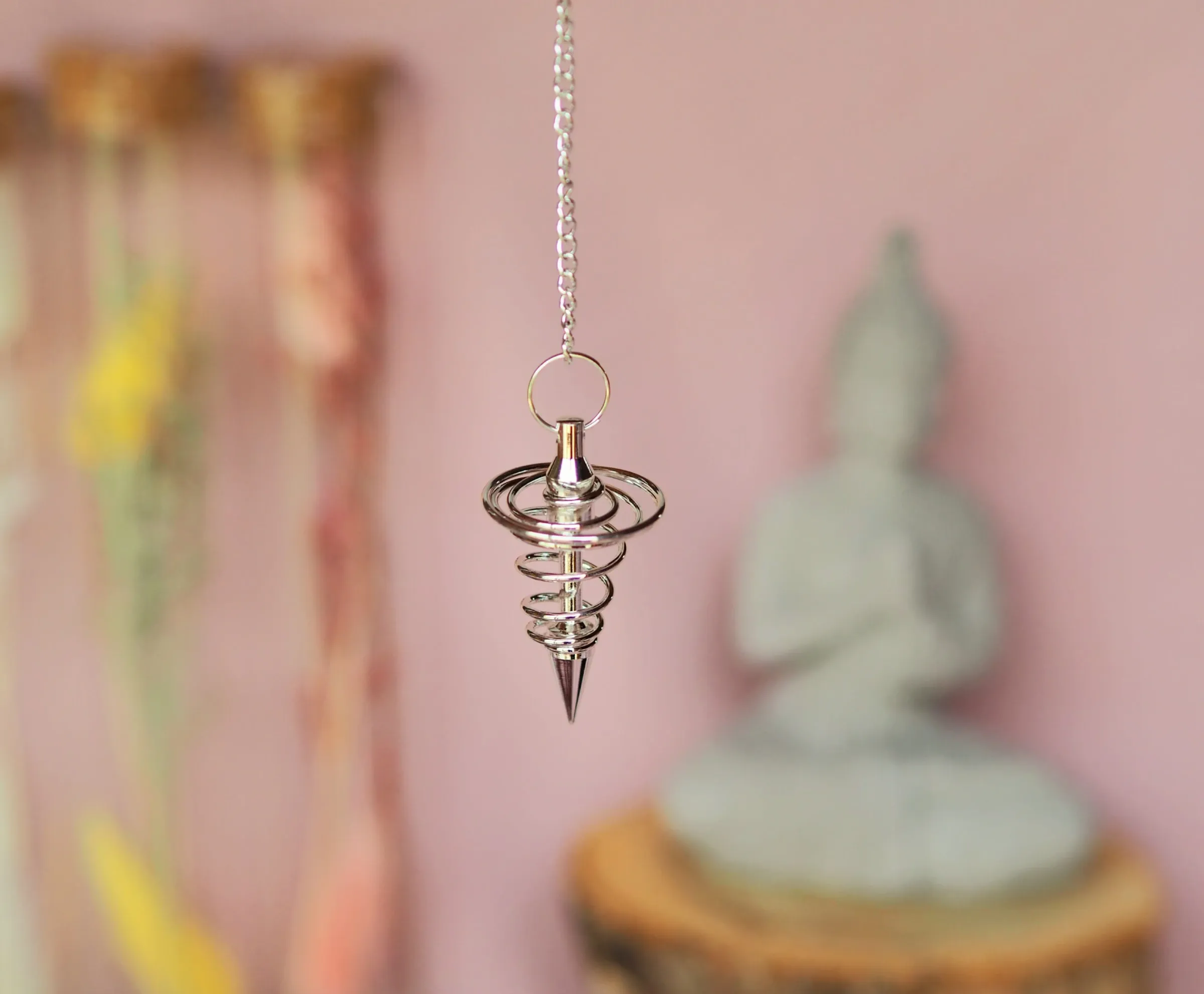 Pendule en acier argenté en forme de spirale qui se resserre vers une pointe, suspendu à une chaînette fine