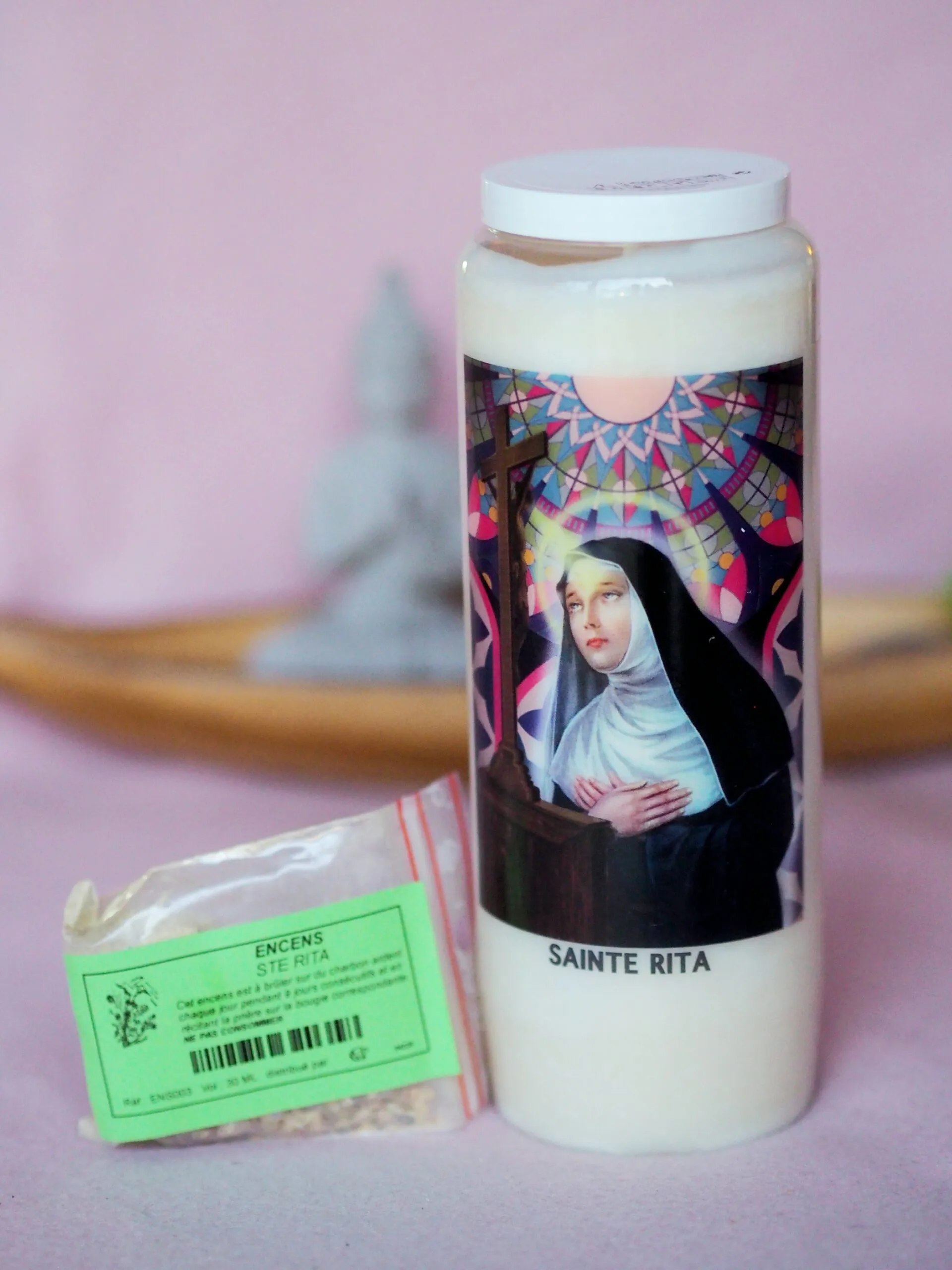 Bougie blanche de neuvaine à l’effigie de sainte Rita, à côté d’un sachet d’encens Sainte Rita